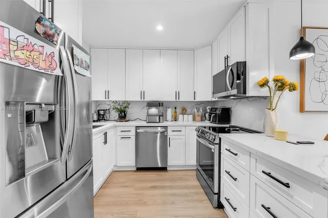 a kitchen with white cabinets and stainless steel appliances