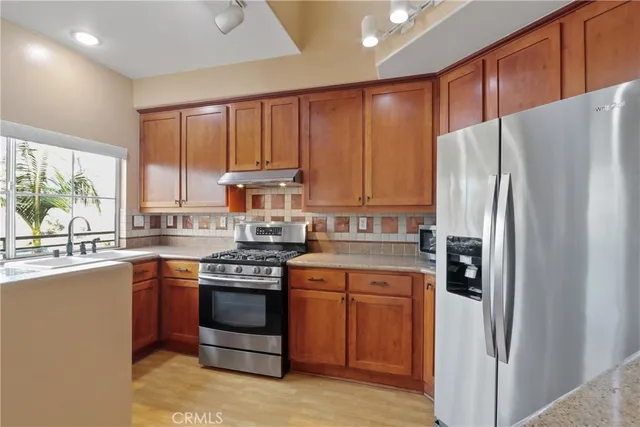 a kitchen with stainless steel appliances granite countertop a refrigerator and a stove top oven