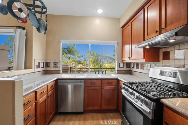 a kitchen with stainless steel appliances granite countertop a sink a stove and a wooden cabinets