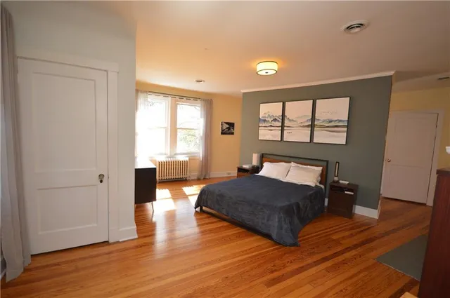 a spacious bedroom with a bed windows and wooden floor