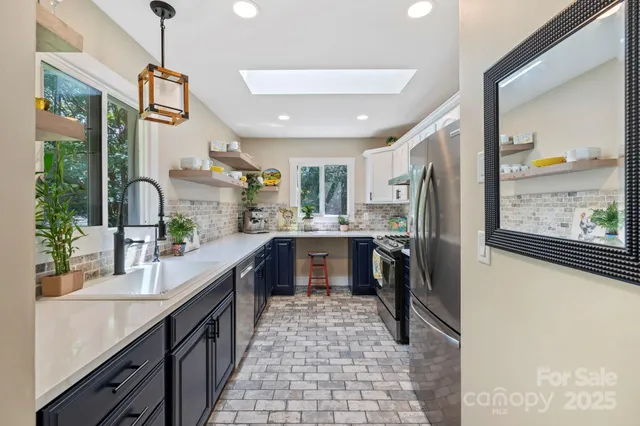 a large kitchen with stainless steel appliances kitchen island granite countertop a refrigerator and a sink