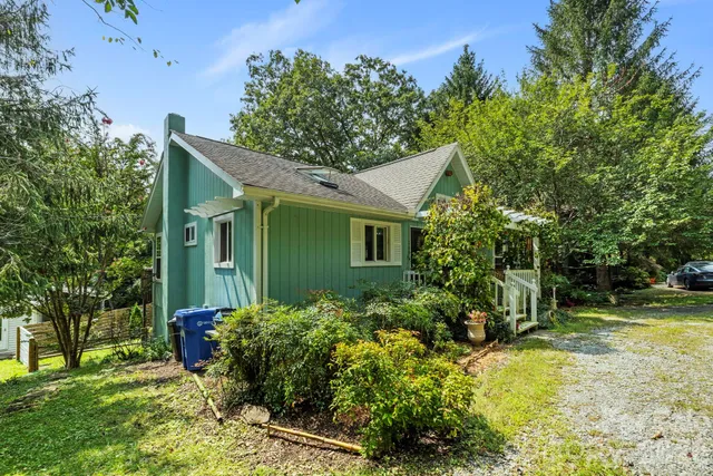 a view of a house with a big yard plants and large tree