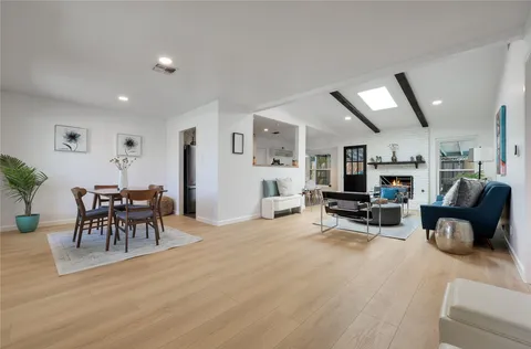 a living room with furniture and a dining table with wooden floor