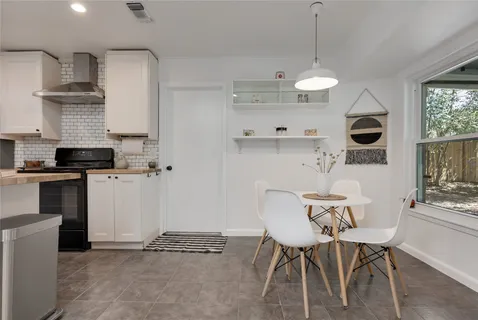 a kitchen with stainless steel appliances granite countertop a stove a refrigerator a sink a dining table and chairs with wooden floor