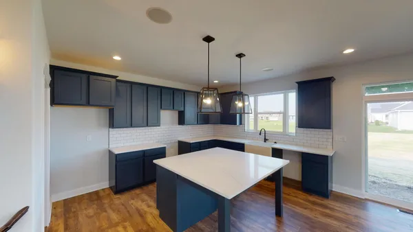 a kitchen with kitchen island a wooden floor and white cabinets