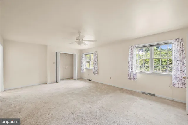 an empty room with windows and chandelier fan