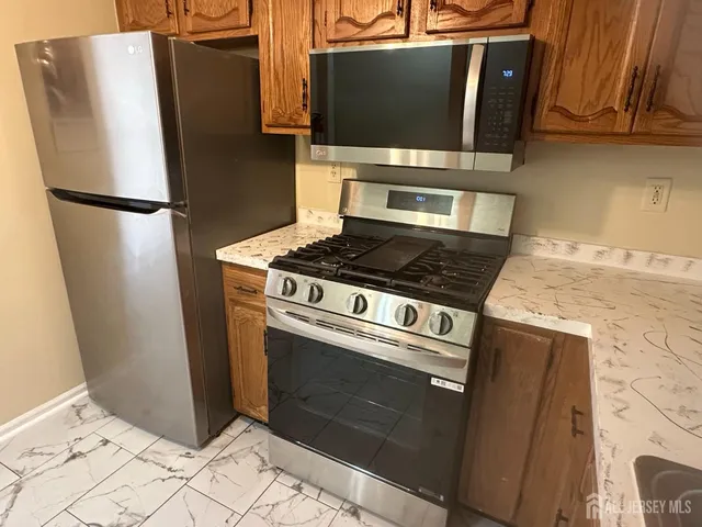 a kitchen with stainless steel appliances granite countertop a refrigerator stove and microwave