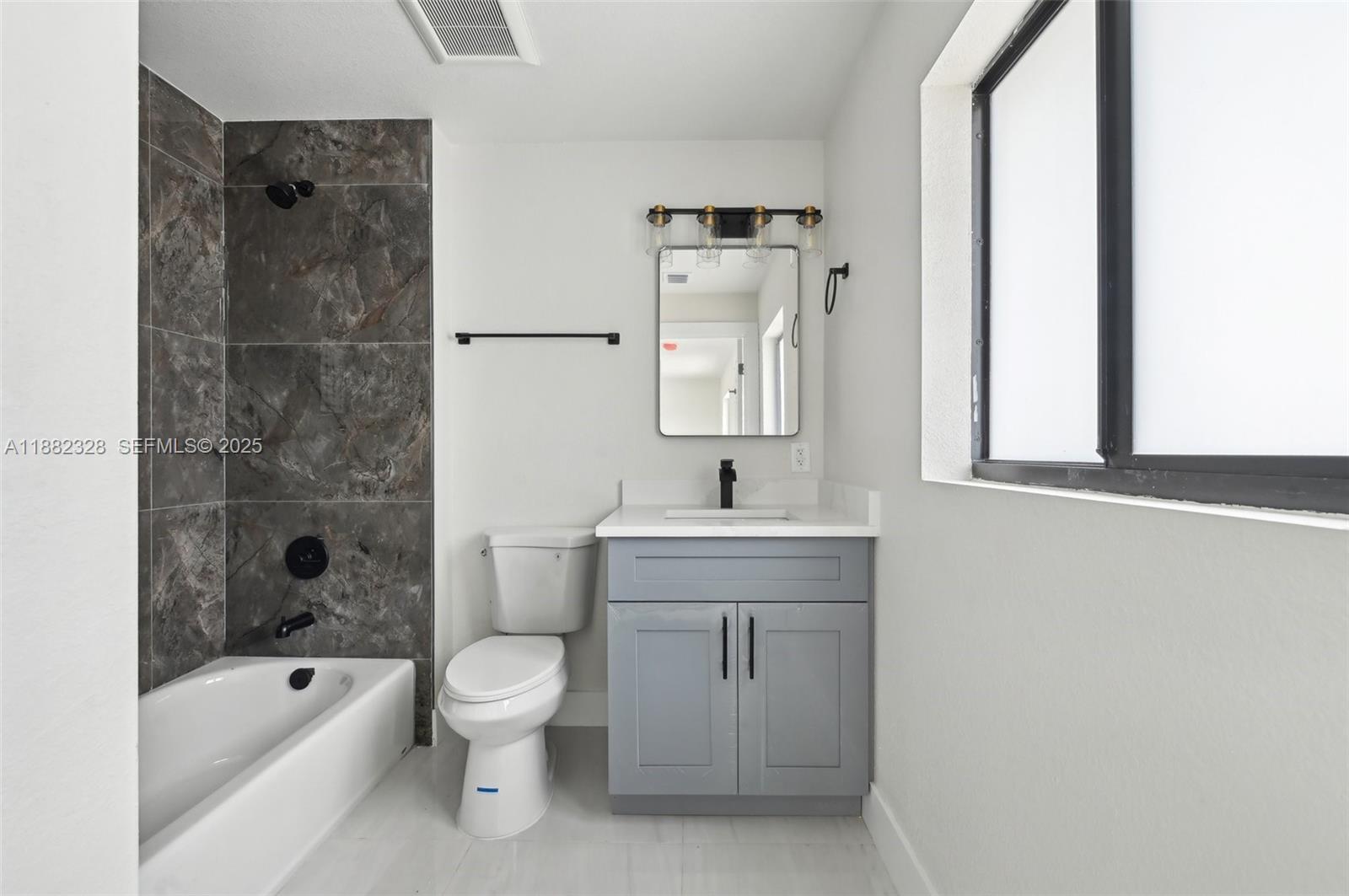 10344 Northwest 29th Avenue, Unit 10344 Miami, FL 33147 - Photo 12 of 12 a bathroom with a bathtub shower sink mirror and toilet