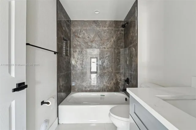 a bathroom with a granite countertop bathtub shower sink vanity and toilet