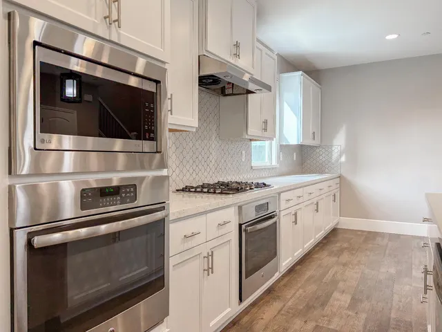 a kitchen with granite countertop a white refrigerator oven a sink and cabinets