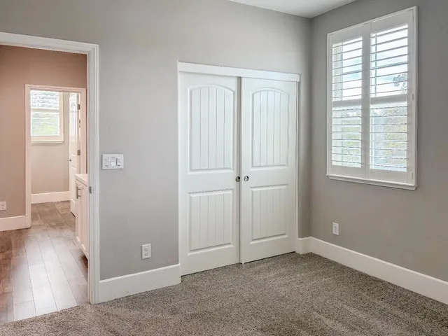 an empty room with wooden floor closet and windows