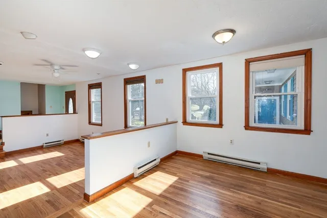 a view of an empty room with window and wooden floor