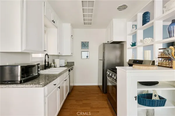 a kitchen with stainless steel appliances granite countertop a refrigerator a stove and a sink