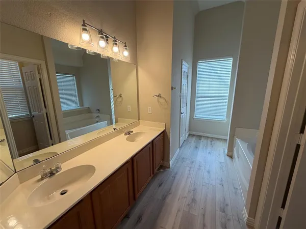 a bathroom with a double vanity sink a toilet a mirror and shower