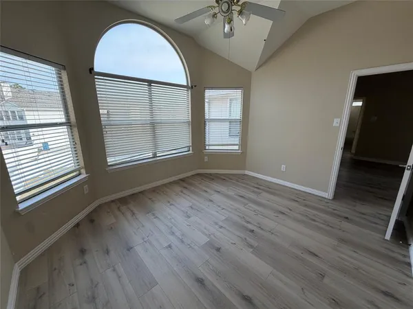 a view of an empty room with a window and wooden floor