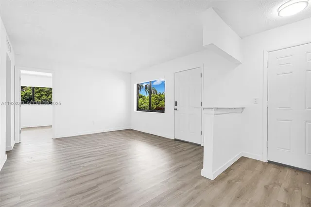 an empty room with wooden floor mirror and windows