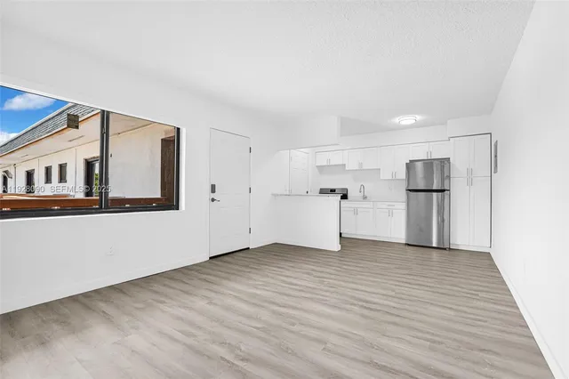a view of a kitchen with refrigerator and white cabinets
