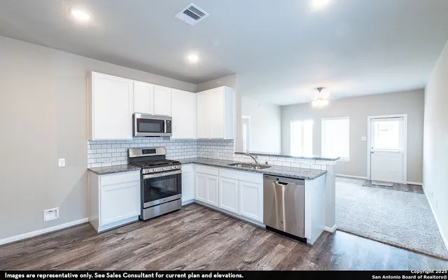 a kitchen with stainless steel appliances granite countertop a stove top oven a sink and white cabinets