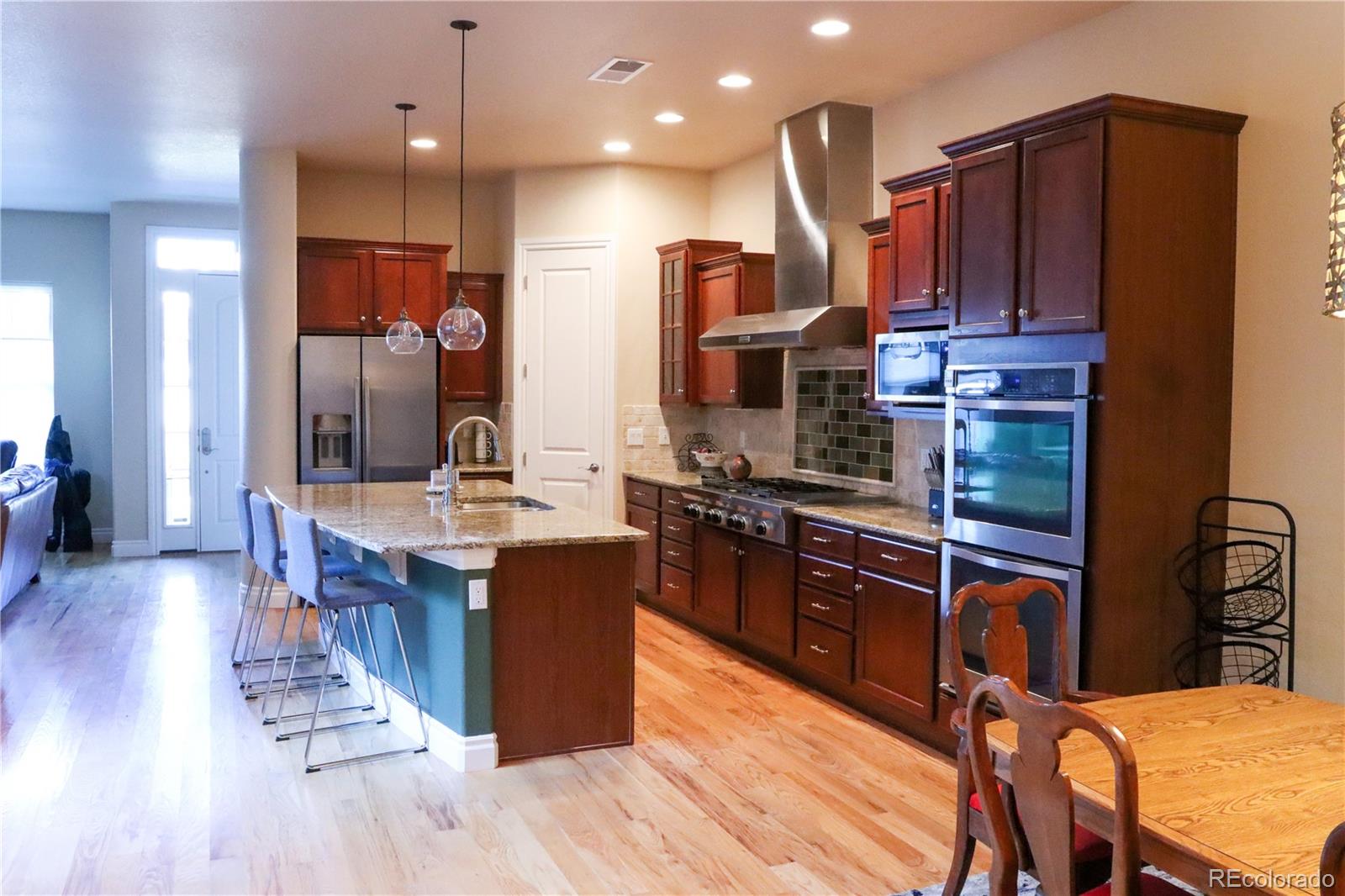 a kitchen with stainless steel appliances kitchen island granite countertop wooden floors wooden cabinets