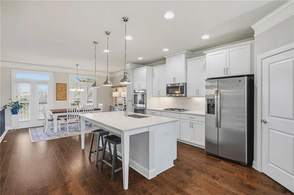 a kitchen with stainless steel appliances a dining table chairs stove refrigerator and cabinets