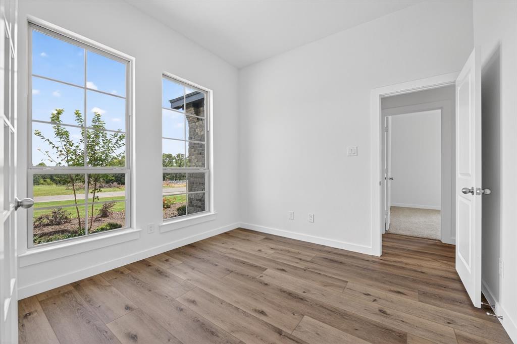 416 McAlpine Drive Springtown, TX 76082 - Photo 5 of 40 Bright room featuring two large windows, wood-finish flooring, white walls, and a white door