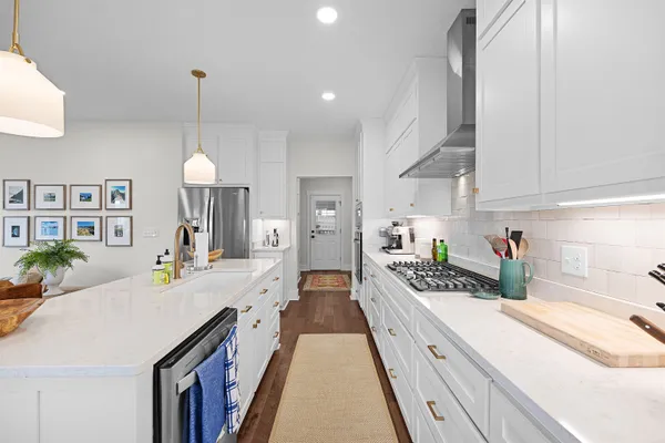 a large kitchen with kitchen island white cabinets and stainless steel appliances