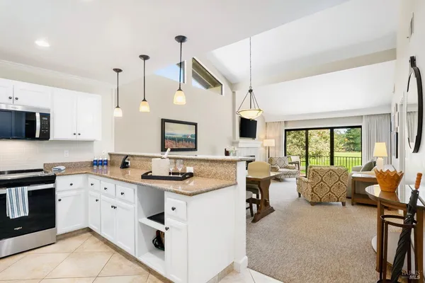a kitchen with stainless steel appliances kitchen island granite countertop a stove and white cabinets