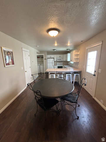 432 Spring Lane Logan, UT 84341 - Photo 7 of 22 Dining area featuring dark wood finished floors, separate washer and dryer, and a textured ceiling