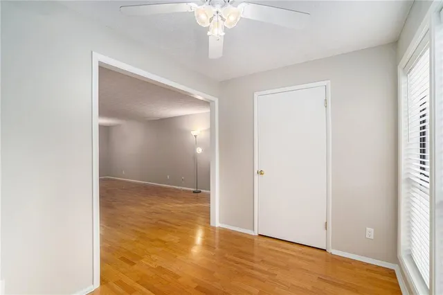 a view of an empty room with wooden floor and a window