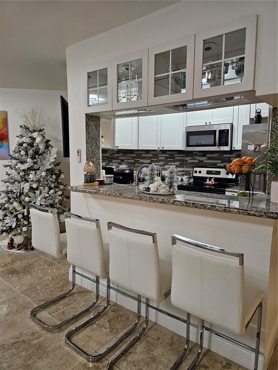 9781 Southwest 138th Avenue, Unit DB1R Miami, FL 33186 - Photo 5 of 16 a kitchen with stainless steel appliances a stove a sink cabinets and a dining table