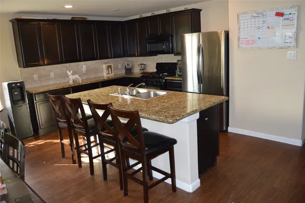 a kitchen with stainless steel appliances granite countertop a refrigerator a stove a sink a dining table and chairs