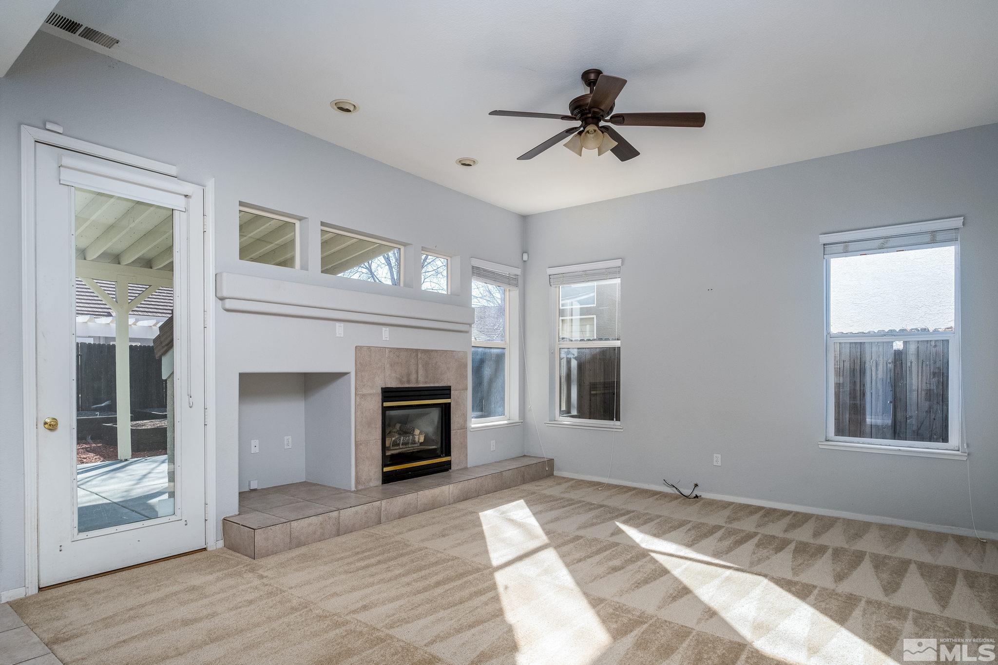 9430 Oakley Lane Reno, NV 89521 - Photo 13 of 28 a view of a livingroom with a fireplace a ceiling fan and windows