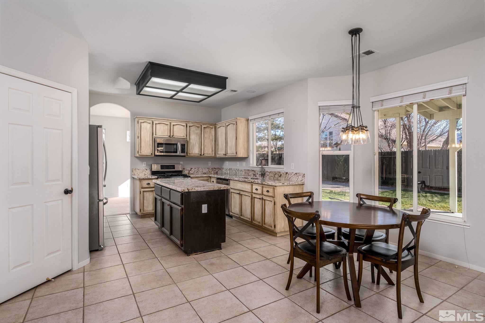 9430 Oakley Lane Reno, NV 89521 - Photo 9 of 28 a kitchen with stainless steel appliances granite countertop a stove top oven a sink a dining table and chairs