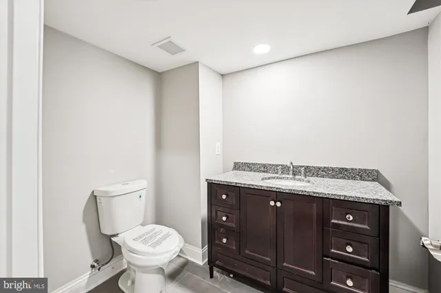 a bathroom with a granite countertop toilet and a sink
