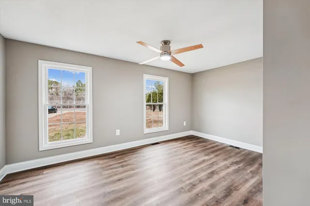 a view of an empty room with a window and wooden floor