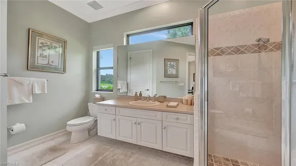 a spacious bathroom with a granite countertop sink a toilet and a mirror