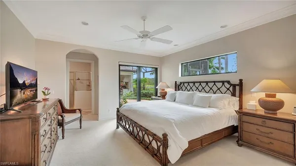 a bedroom with a bed a mirror and a flat tv screen on dresser