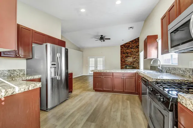 a kitchen with stainless steel appliances granite countertop a stove refrigerator sink and microwave