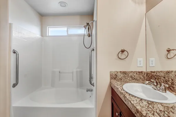 a bathroom with a granite countertop sink a mirror and a bathtub