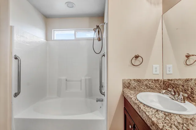 a bathroom with a granite countertop sink a mirror and a bathtub