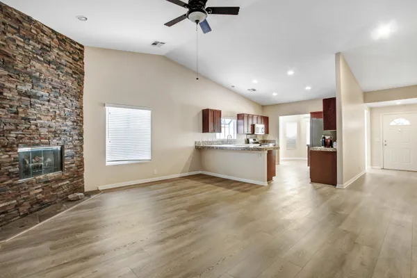 a view of an empty room with a window and kitchen view