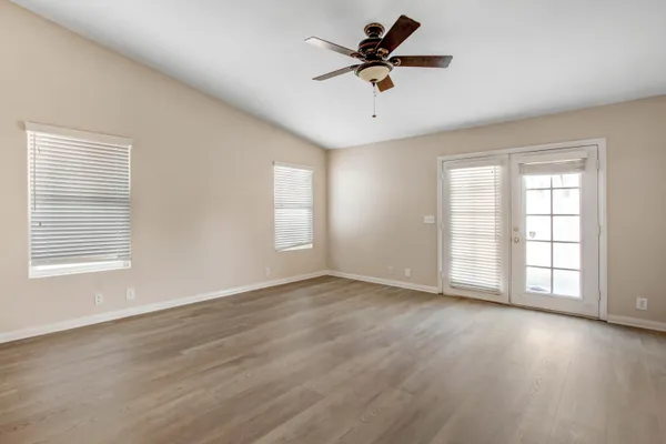 a view of an empty room with a window and wooden floor