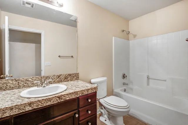 a bathroom with a granite countertop toilet a sink and a mirror