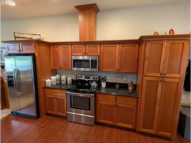 a kitchen with stainless steel appliances granite countertop a refrigerator and a stove top oven