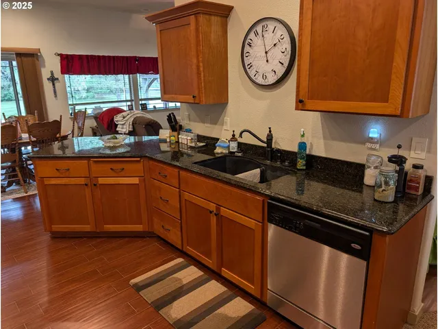 a kitchen with stainless steel appliances granite countertop a sink a stove and a wooden cabinets