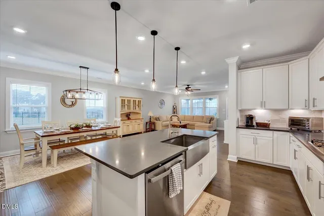 a kitchen with stainless steel appliances granite countertop a sink a stove a refrigerator and island with wooden floor