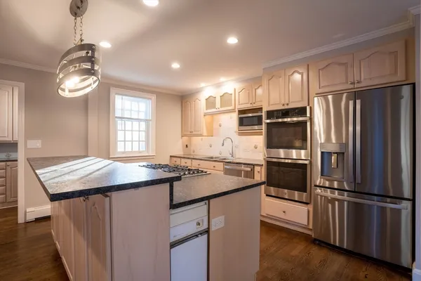 a kitchen with granite countertop stainless steel appliances a refrigerator cabinets and wooden floor