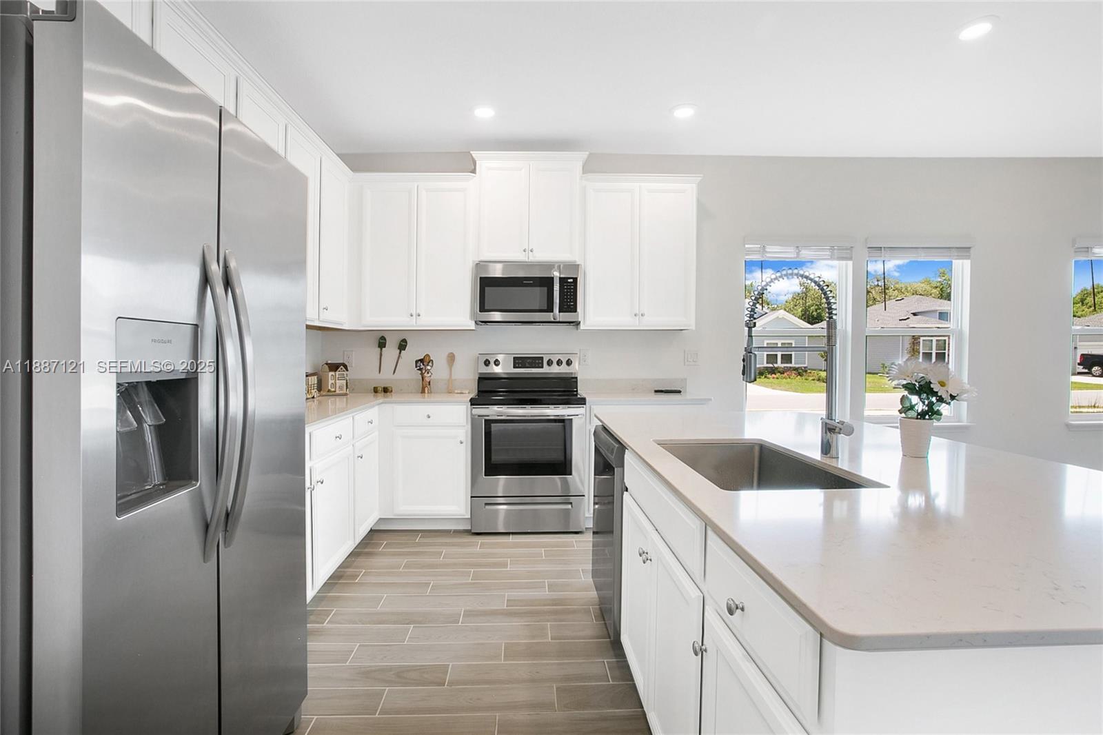 7796 Southwest 74th Loop Ocala, FL 34481 - Photo 10 of 20 a kitchen with stainless steel appliances granite countertop a refrigerator a stove and a sink with wooden floor