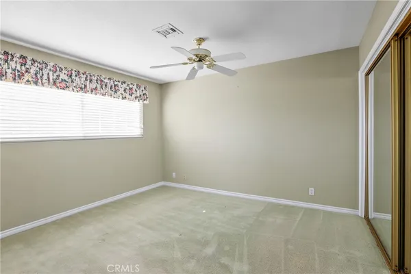 an empty room with a window and a fan