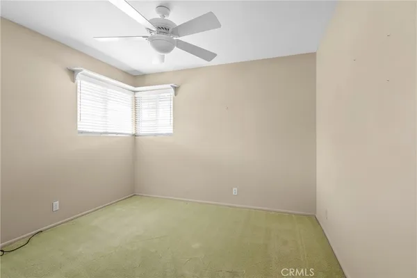 an empty room with a window and a ceiling fan